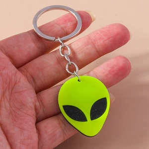 Detailed close-up of a neon green alien head keychain made of soft silicone material