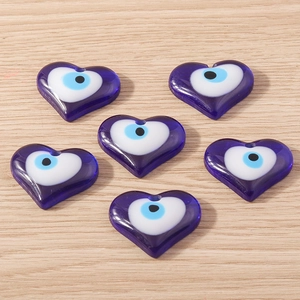 Gros plan de pendentifs en verre bleu en forme de cœur avec œil maléfique pour bijoux DIY