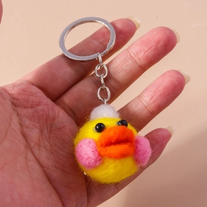 Detailed close-up of handmade yellow wool felt duck keychain with silver ring connector