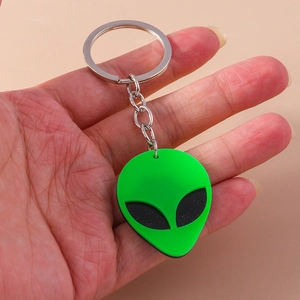 Detail of neon green alien keychain with silver metal ring held in hand