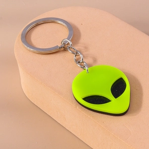Close-up of a punk style fluorescent green alien face keychain with metal ring