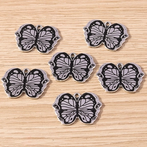 Detail view of black enamel butterfly charms with skull wing patterns for DIY jewelry
