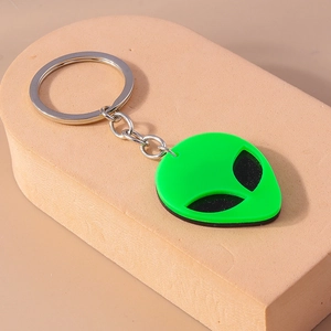 Detail shot of a neon green silicone alien keychain with black eyes and silver metal rings
