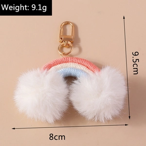 Detail of handmade rainbow keychain with white fluffy pom poms and gold lobster clasp