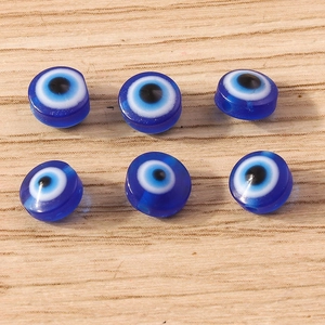 Detail of blue resin evil eye beads for DIY jewelry making on wood background