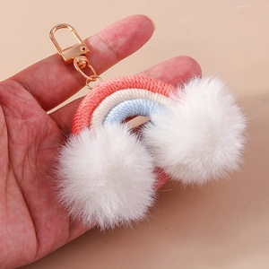 Close-up of handmade rainbow keychain with pink cotton ropes and white fuzzy pom poms