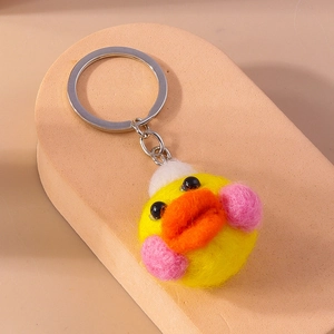 Close-up of handmade yellow wool felt duck keychain with silver ring on display stand