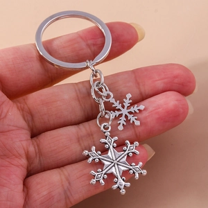 Macro shot of silver metal snowflake pendants and key ring held by a person