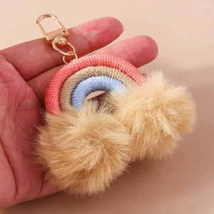 Detail of handmade rainbow keychain with colorful woven rope and soft khaki pom poms