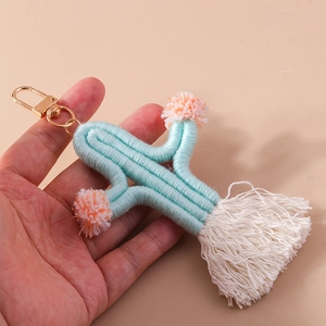 Handheld view of woven cactus keychain with soft mint rope and colorful tassels