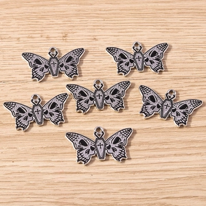 Gothic butterfly pendants featuring skull wings and coffin cross motifs on wood background