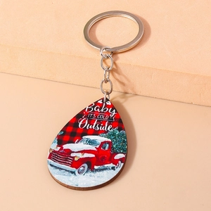 Dettaglio portachiavi natalizio in legno con camion rosso vintage e scritte su sfondo beige