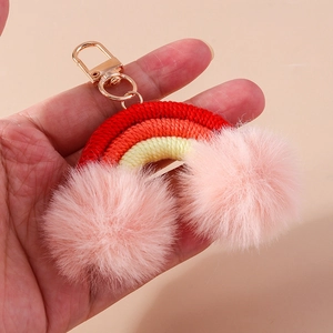 Rainbow bag charm featuring woven cotton cords and soft pink pompom accents with gold clasp