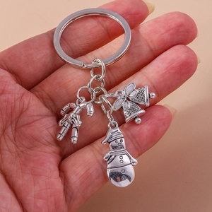 Close-up of Christmas keychain charms featuring silver snowman, bells, and candy cane