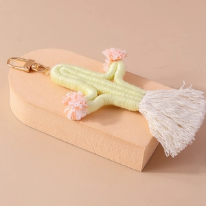 Detailed close-up of handmade green woven cactus keychain with soft pink tassels