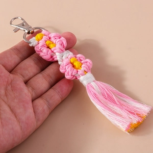 Macro view of handmade woven flower keychain with pink gradient tassels and silver clasp