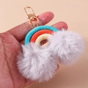 Detail view of handmade rainbow keychain with colorful woven rope and soft fur pom poms
