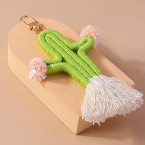 Close-up of handmade woven cactus keychain with white tassels and gold lobster clasp
