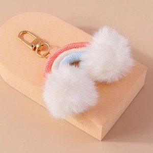 Detail of handmade woven rainbow keychain with soft white pom poms and golden lobster clasp