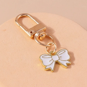 Detailed close-up of a white enamel bow charm with a gold-plated lobster clasp