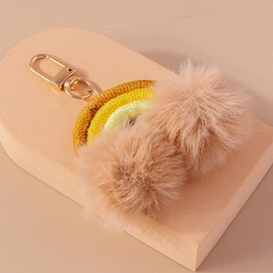 Detail of handmade rainbow keychain with yellow pompoms and gold spring clip