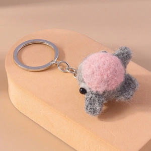 Detail of handmade wool felt grey animal keychain with pink accents and silver metal ring