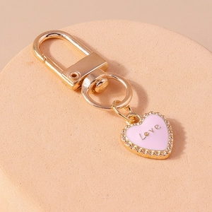 Close-up of golden lobster clasp with pink enamel heart pendant featuring Love engraving