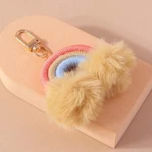 Detail of handmade rainbow keychain with pastel woven cords and soft plush pom poms