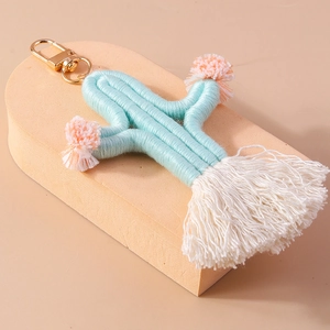 Detail of handmade blue knitted cactus keychain with pink pom-poms and white tassels