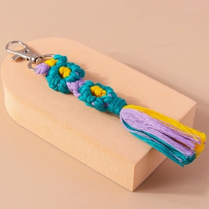 Detailed macro view of handmade woven flower keychain with colorful cotton tassels and silver clasp