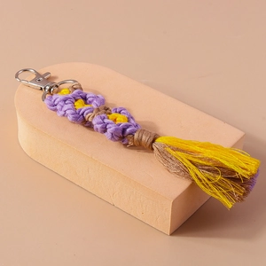 Detailed close-up of handmade woven flower keychain with purple yellow petals and fringe tassel