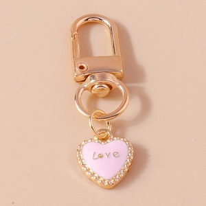 Golden keychain featuring a pink heart pendant with Love inscription on pink background