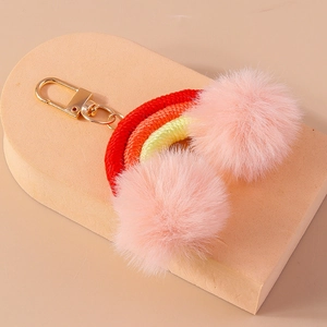 Close-up of a handmade rainbow keychain with colorful woven rope and soft pink faux fur pom poms