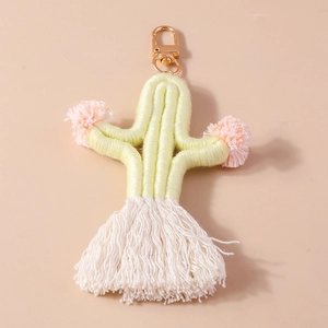 Detailed view of yellow woven cactus keychain with white tassels and gold metal clip