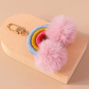 Close-up of creative rainbow keychain with pink pompoms and golden lobster clasp