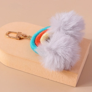 Detailed macro view of handmade woven rainbow keychain with soft grey pompom tassels