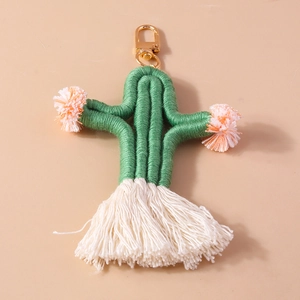 Detail of handmade woven cactus keychain with soft pom poms and white cotton tassels