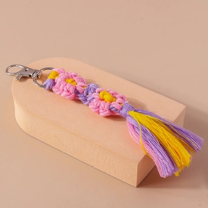 Detailed macro view of handmade woven flower keychain with vibrant pink and purple tassels