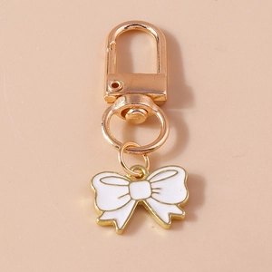 Detailed view of champagne gold bow keychain with white enamel drop oil finish