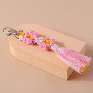 Detailed view of handmade woven flower tassel keychain with pink petals and silver clasp