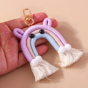 Detailed macro view of handmade rainbow keychain with purple ears and white cotton tassels