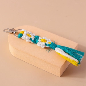 Macro view of handmade woven daisy tassel keychain with silver metal lobster clasp