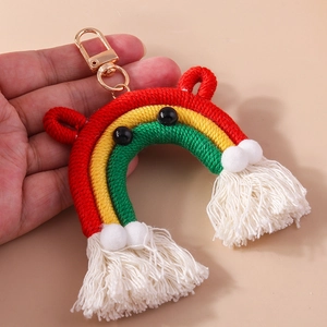 Handheld view of a colorful handmade woven rainbow keychain with white tassels and pom poms