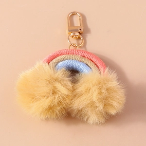 Detail of handmade rainbow keychain with colorful woven rope and soft yellow pom-poms