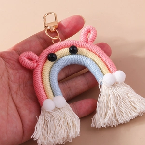 Close-up of handmade rainbow keychain with colorful cotton rope, pompoms and white tassels