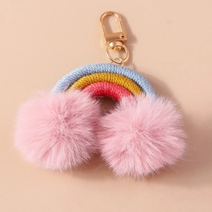 Close-up of rainbow bag charm with blue yellow red braided cord and pink pom-poms