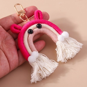Detail of handmade woven rainbow keychain with pink cotton fringes and golden metal clasp