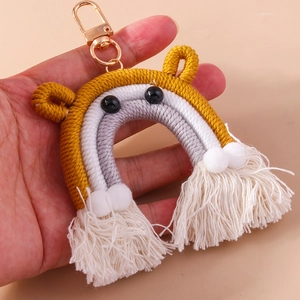 Detail of handmade woven rainbow keychain with yellow and grey rope and white tassels