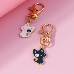 Pendentifs chats mignons noir et blanc avec porte-clés en métal doré sur fond rose