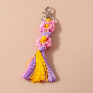 Detailed macro view of handmade woven flower keychain with colorful tassels and silver clasp